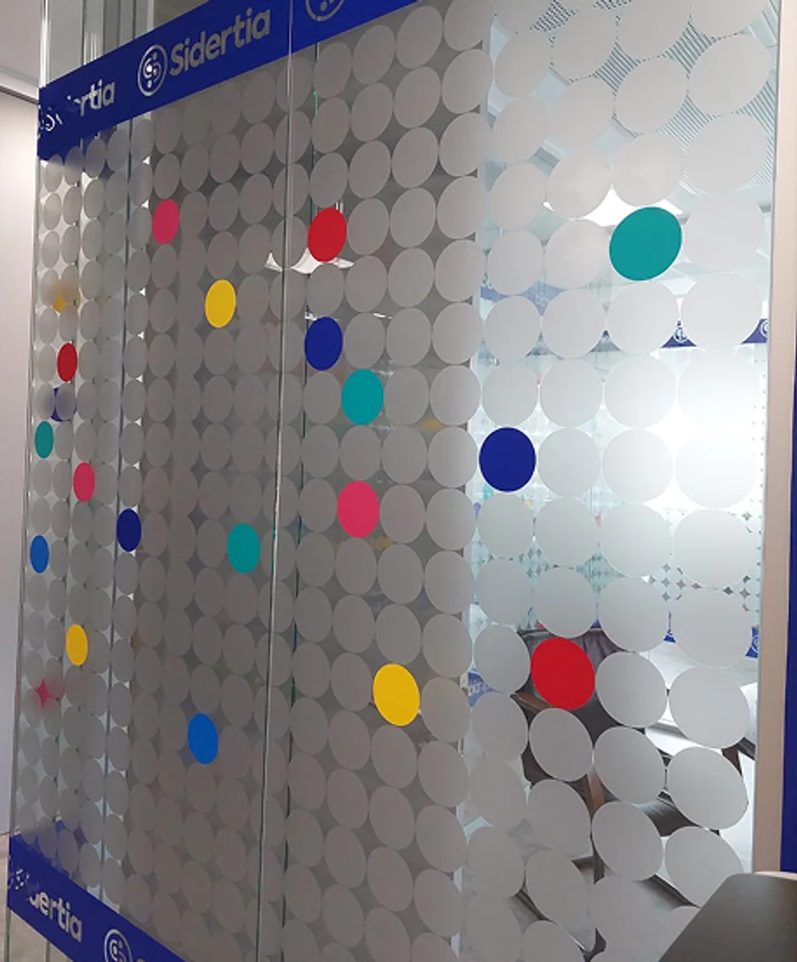 A corridor of glass walls and a close-up of the frosted and coloured dots on the glass